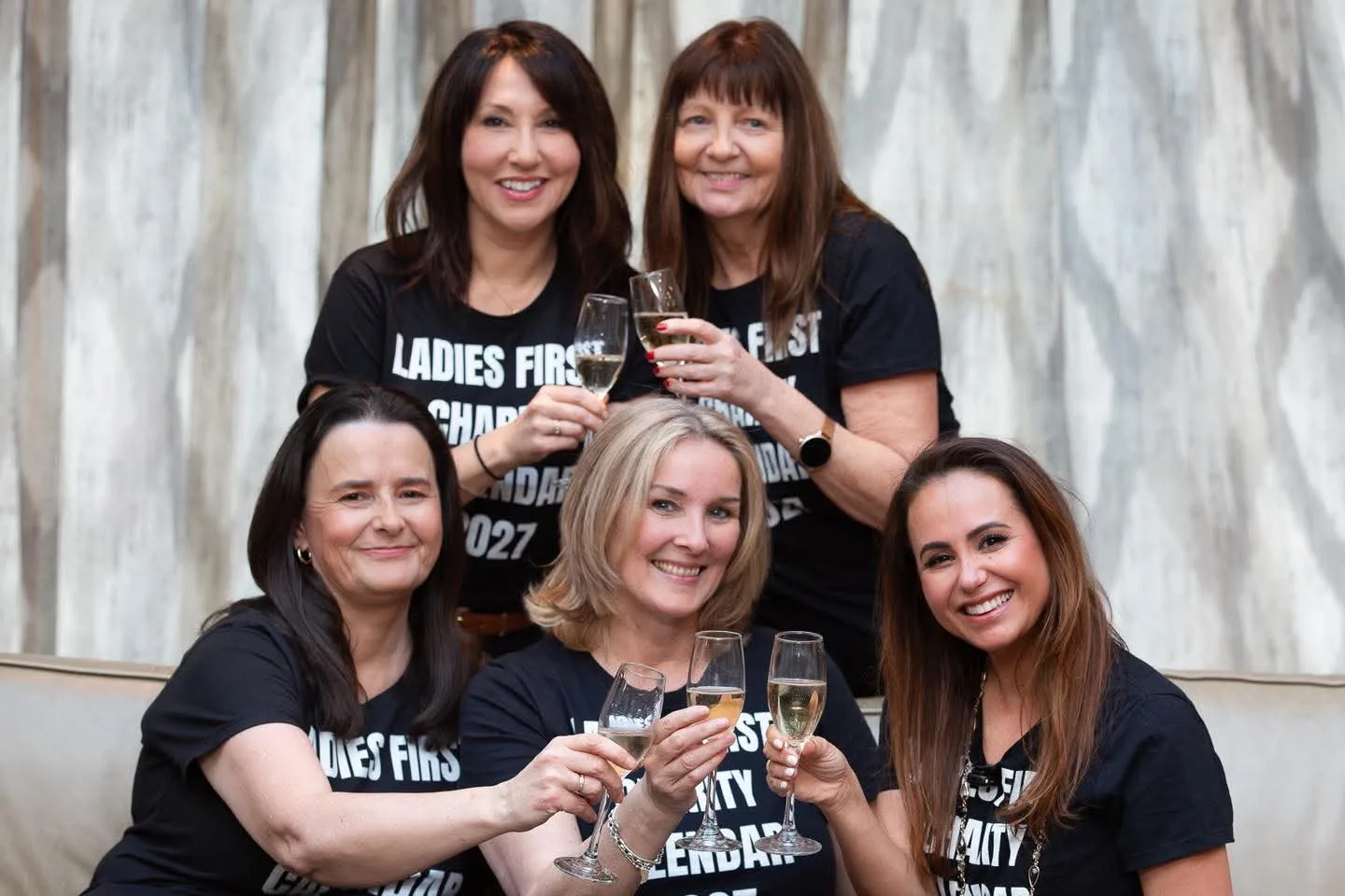 Five of the women raising a glass in their 2027 calendar shirts